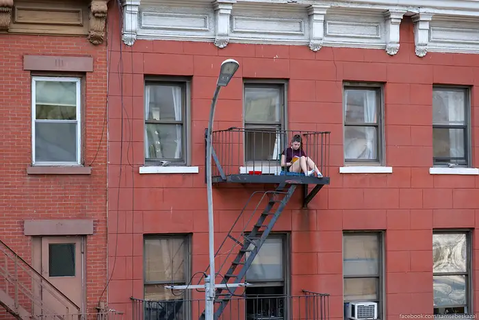 a woman reads out on a fire escape